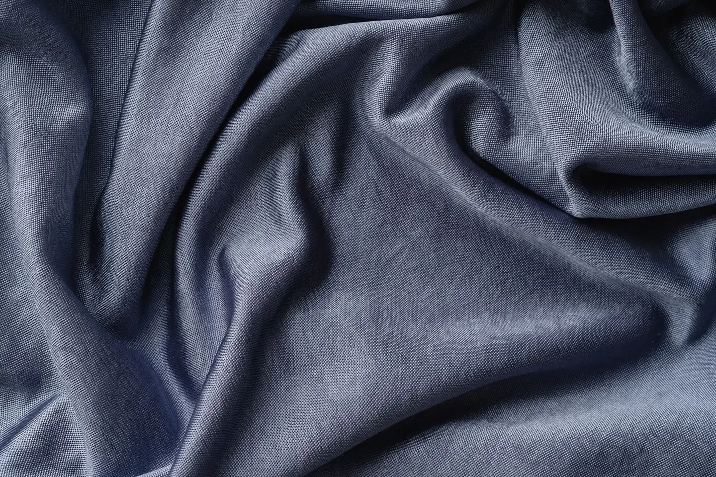 A close fold of slate blue Suvin cotton, showing its fine weave and lustre